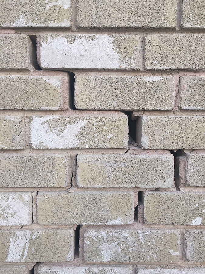Close-up of a light-colored brick wall showing a large,